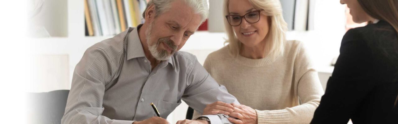 Older couple signing documents to hire an attorney