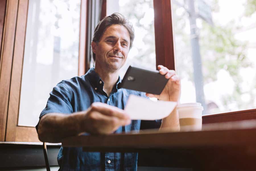 man depositing check with mobile phone