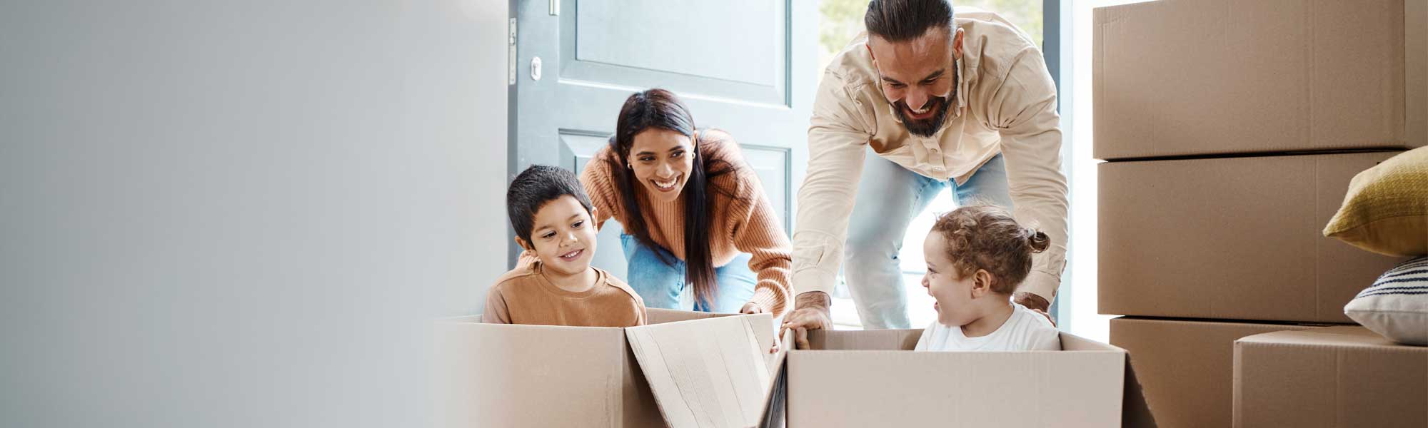 First Time home Buyer - 155 years of welcoming you home. Family with moving boxes having fun.